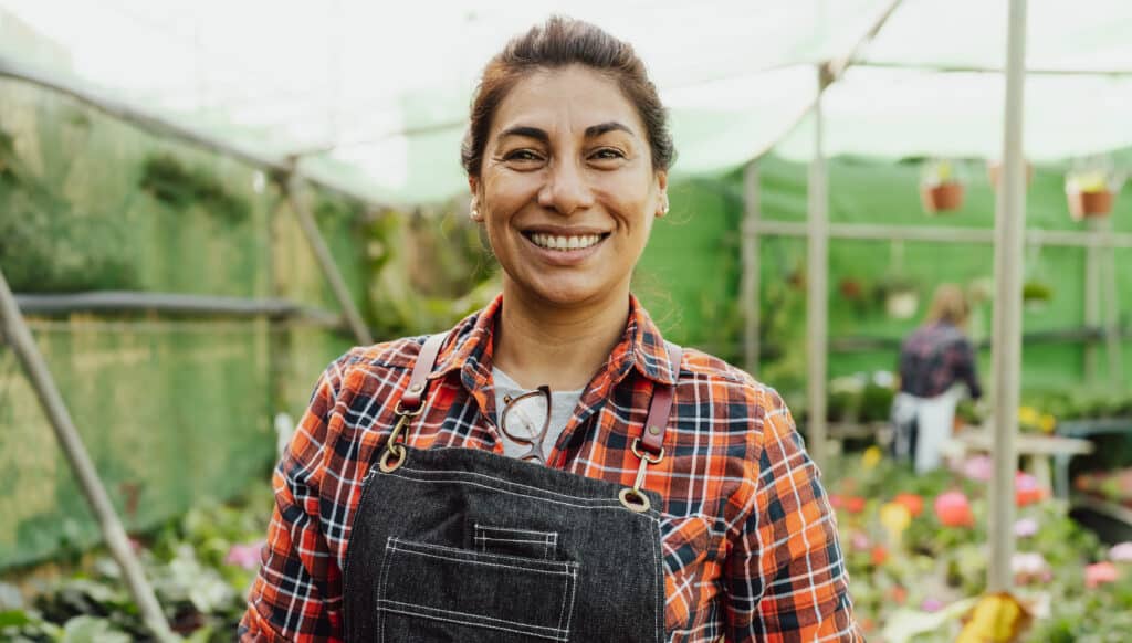 Happy woman smiling front of camera while working in greenhouse